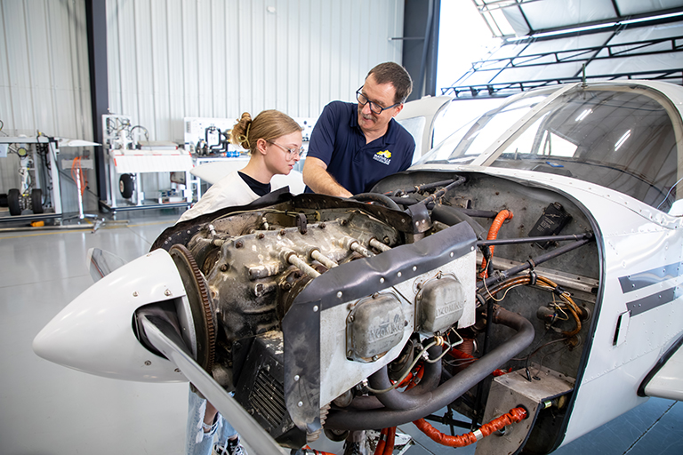student and instructor looking at plane engine