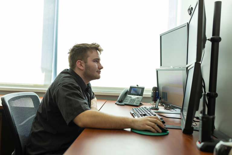 Student working on a computer with multiple screens