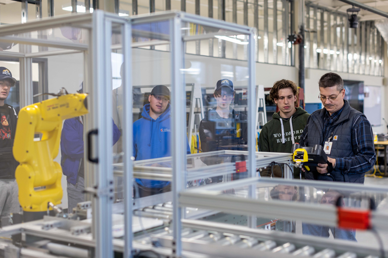 group of students looking at a machine in the machinery lab