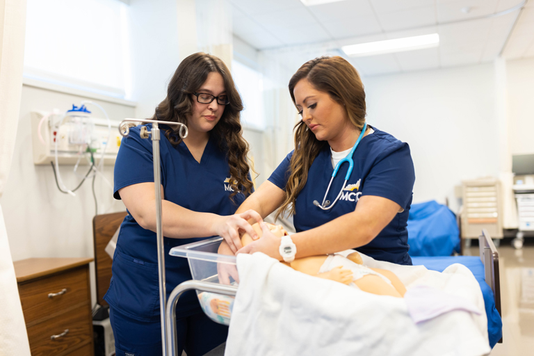 students practicing on a mannequin baby