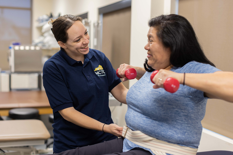 student working with a client using weights