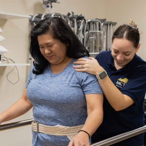 Physical therapist assistant instructing patient through a therapy exercise.