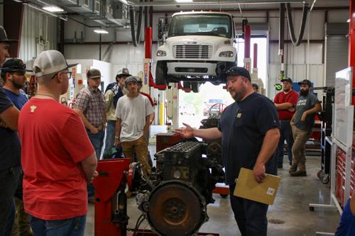 group of men standing around a garage with a semi in the air