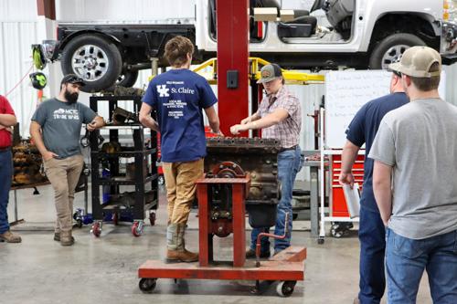 students working on a car while it is held in the air