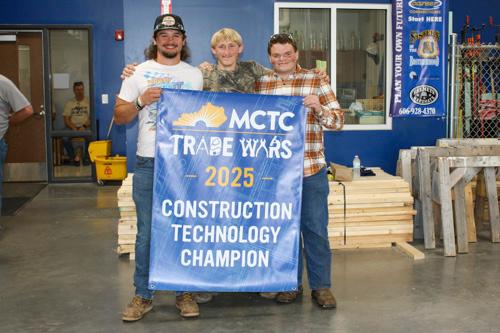 three students holding a banner for their win in the Construction Technology competition