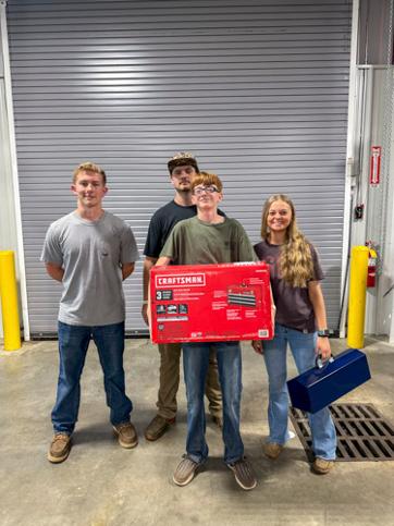 four students holding a large check