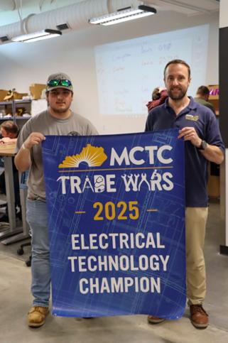 two students holding a banner for their win in the Electrical Technology competition
