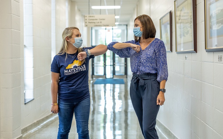 MCTC faculty member and student bumping elbows with masks on