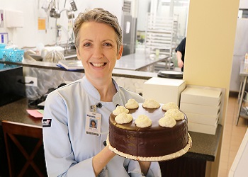 Chef Ann Flora holding a cake made at the Culinary Arts Program Bakery.