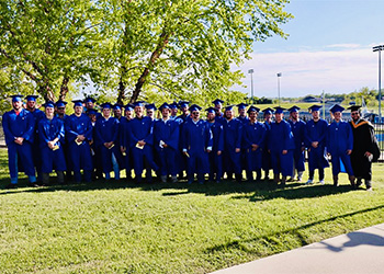HVAC graduates in their blue MCTC cap and gowns with their instructor, Adam Hawkins.