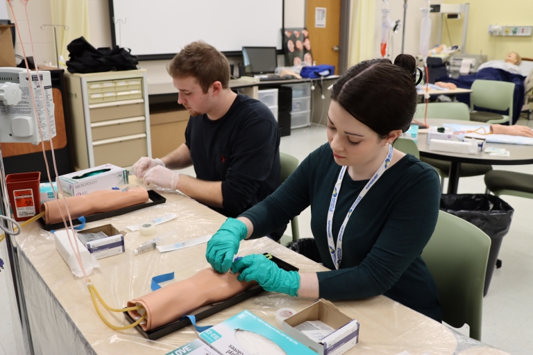 two RN students practicing with placing IV lines