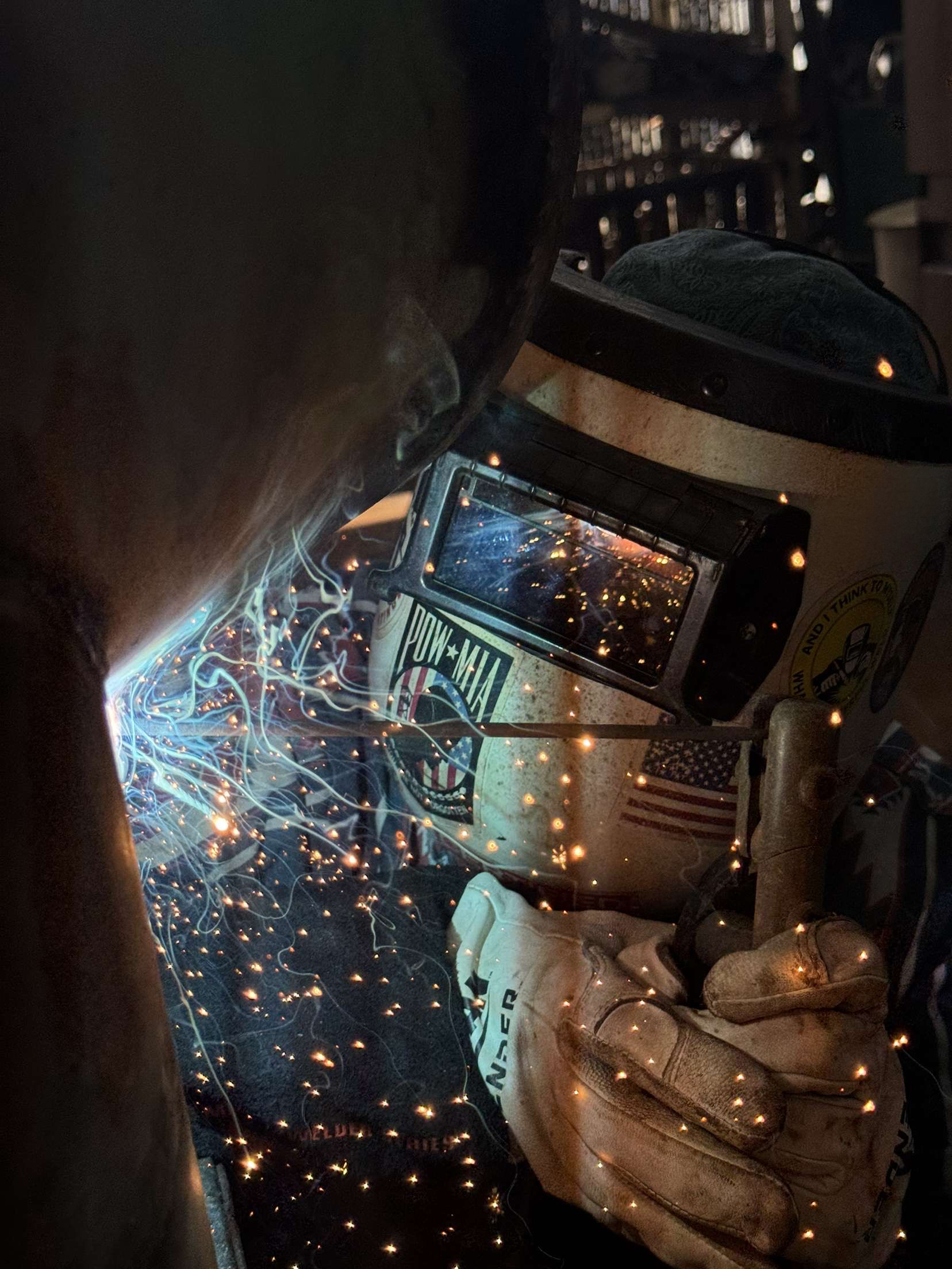 student welding with protective equipment on and sparks flying around