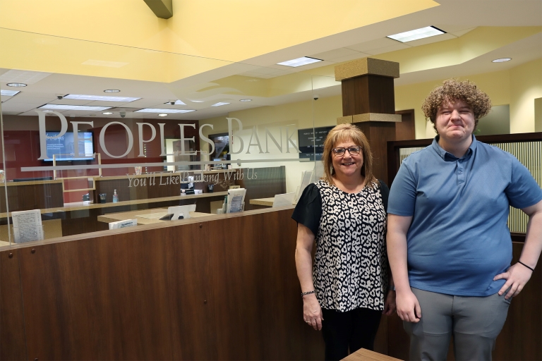 Colby Hurst with supervisor Hollie Poe in front of a People’s Bank of Kentucky in Flemingsburg sign