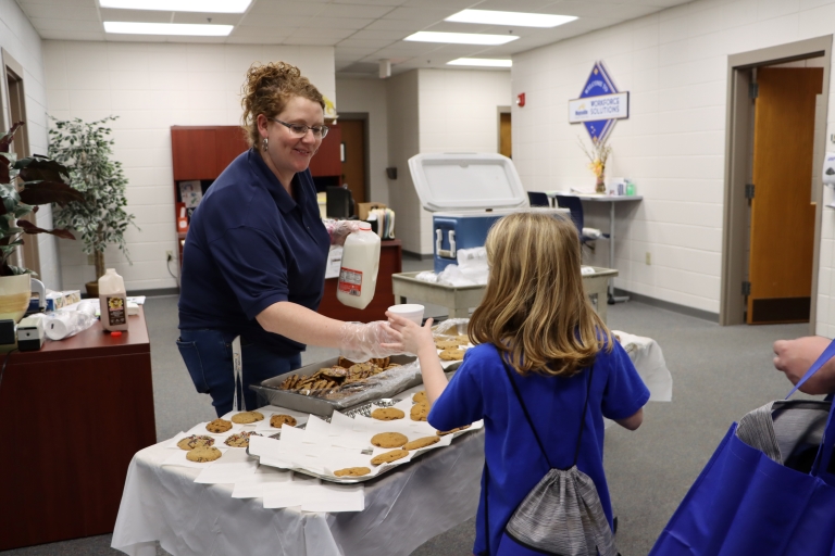 volunteer handing out cookies and milk to a child