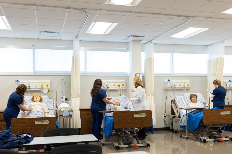 Several groups of nursing students practicing in the Nursing Lab