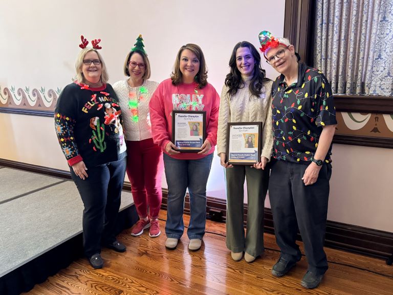 group wearing Christmas sweaters with their awards