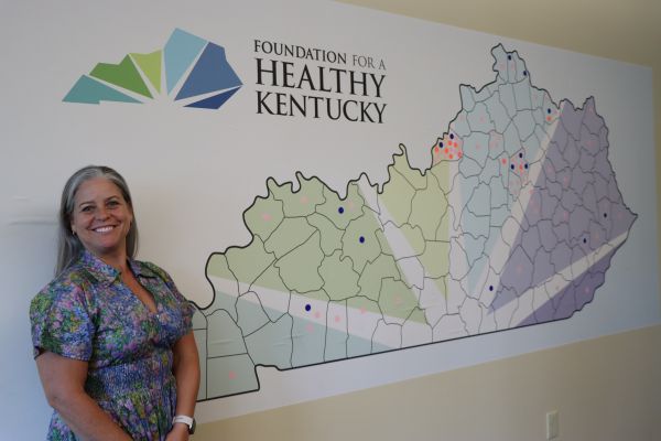 MCTC alumna Allison Adams standing in front of a Foundation for a Healthy Kentucky map.