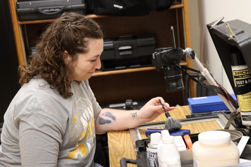 student dusting an object with a little brush in a classroom