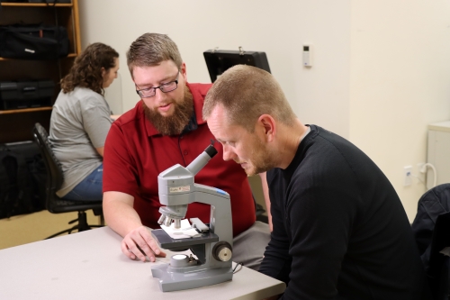 dual credit students looking through a microscope in a classroom