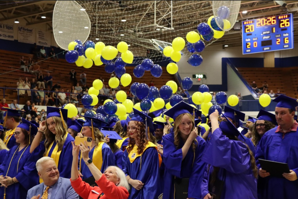 grads at commencement ceremony with balloons above