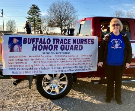 nurse standing beside a Buffalo Trace Nurses Honor Guard banner on the side of a truck