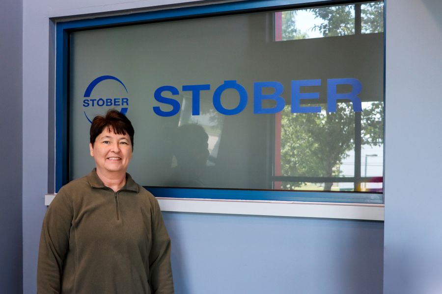 Kay Moss standing in front of a window that displays the Stober company logo.
