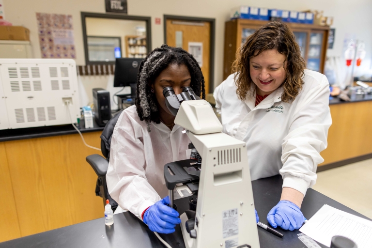 student and instructor looking into a microscope