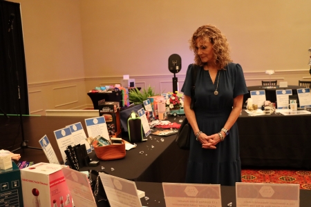woman standing next to the tables full of auction items at the WJM 2026 event