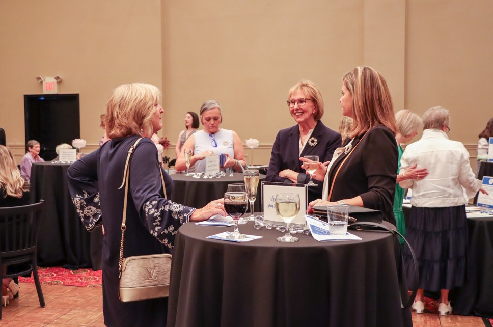 group of women standing around a table, drinking wine, at the 2025 event